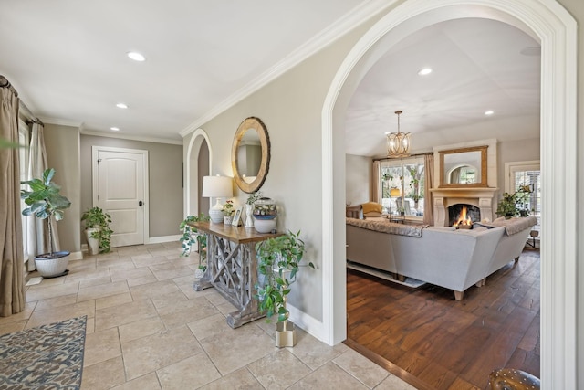 hallway featuring crown molding, light wood-type flooring, and a notable chandelier