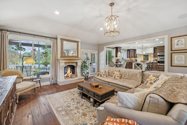 living room with a chandelier, a fireplace, and dark wood-type flooring