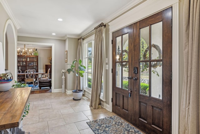 foyer entrance with a chandelier, ornamental molding, and french doors