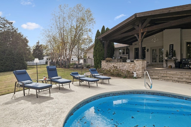 view of pool with french doors, a patio, and a lawn