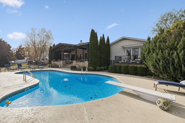 view of swimming pool with a patio area and a diving board