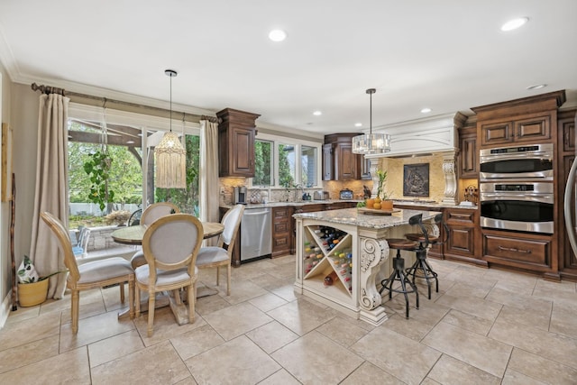 kitchen featuring pendant lighting, a center island, light stone countertops, ornamental molding, and stainless steel appliances