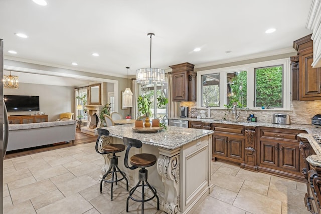 kitchen featuring a breakfast bar, crown molding, sink, light stone countertops, and a kitchen island