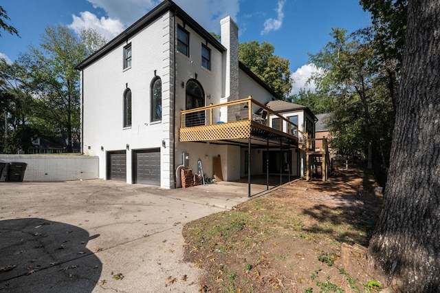 rear view of property featuring a wooden deck and a garage