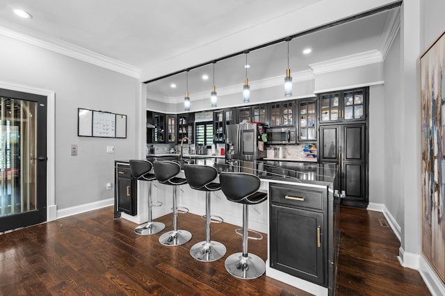 kitchen featuring dark wood-type flooring, hanging light fixtures, stainless steel appliances, decorative backsplash, and a kitchen island