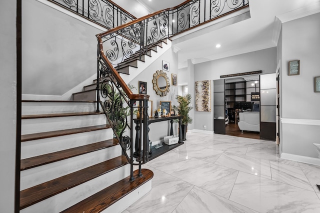 foyer entrance with a towering ceiling and ornamental molding