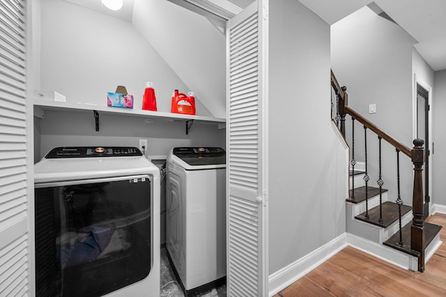 clothes washing area featuring wood-type flooring and washer and clothes dryer