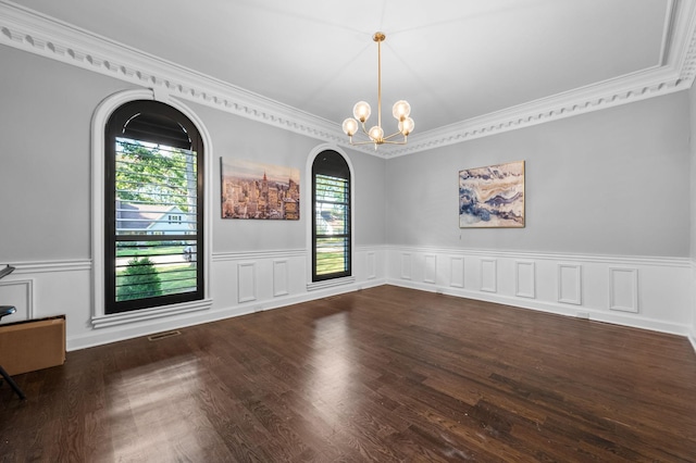 spare room featuring a chandelier, dark hardwood / wood-style floors, and ornamental molding