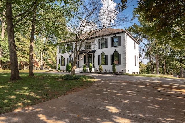 colonial home with a balcony and a front lawn