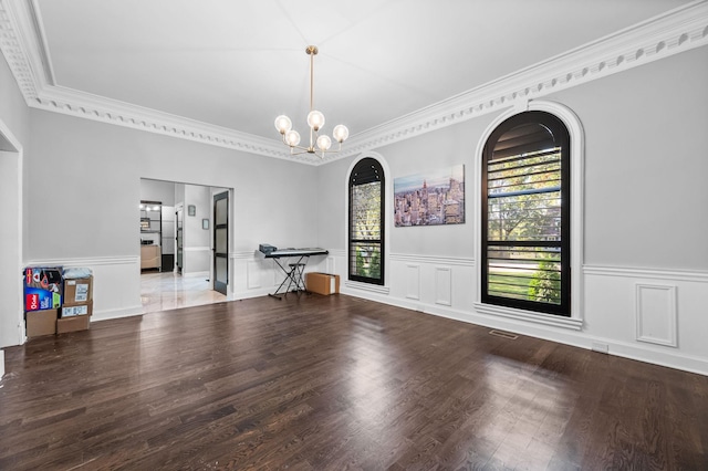 unfurnished room featuring hardwood / wood-style flooring, crown molding, and an inviting chandelier