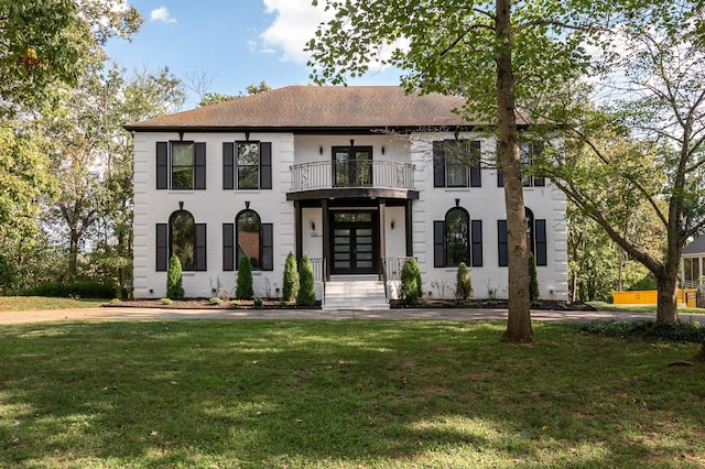 view of front of house featuring a balcony, a front lawn, and french doors