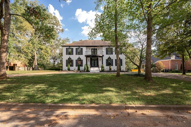 colonial house featuring a balcony and a front yard