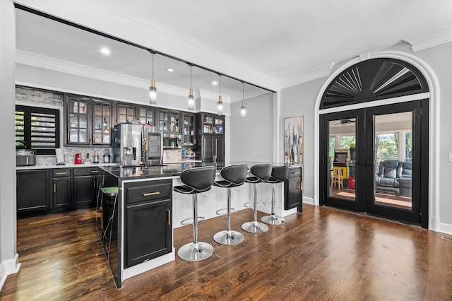 kitchen with hanging light fixtures, tasteful backsplash, a kitchen island, a kitchen bar, and stainless steel fridge with ice dispenser