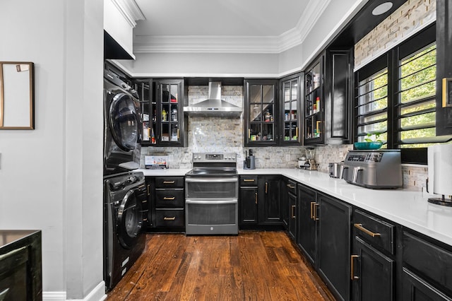 kitchen featuring wall chimney exhaust hood, stacked washing maching and dryer, tasteful backsplash, dark hardwood / wood-style floors, and stainless steel range with electric stovetop