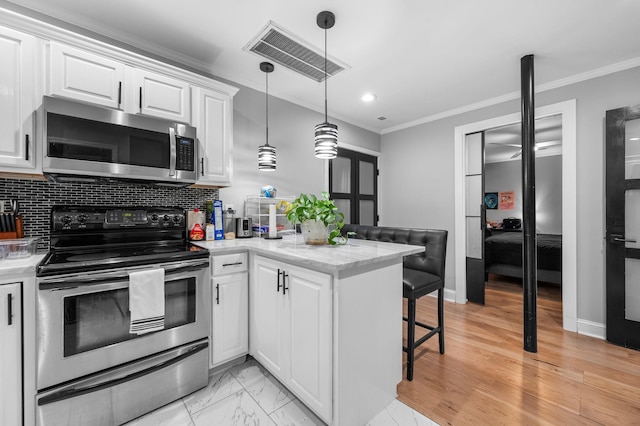 kitchen featuring kitchen peninsula, white cabinetry, crown molding, and stainless steel appliances