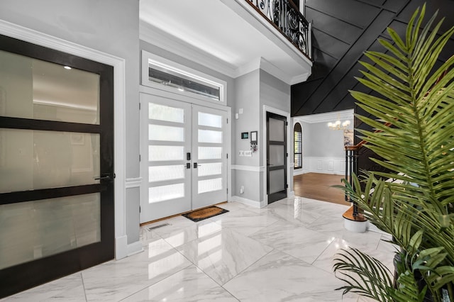 entrance foyer with french doors, a towering ceiling, crown molding, and a notable chandelier