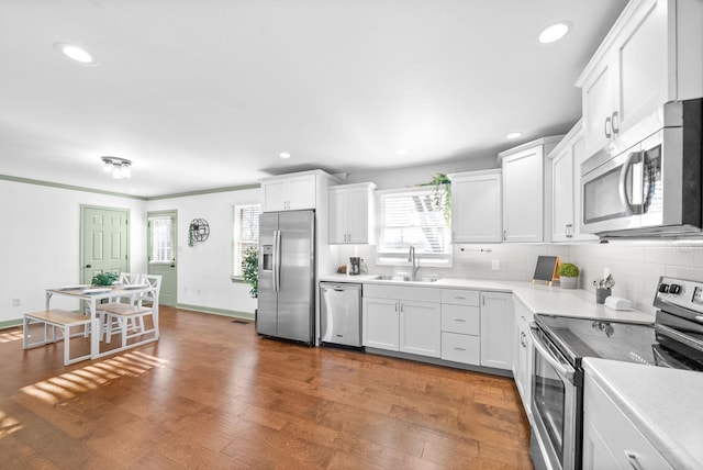 kitchen with sink, dark wood-type flooring, stainless steel appliances, decorative backsplash, and white cabinets