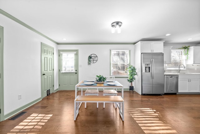 dining area featuring plenty of natural light, dark hardwood / wood-style flooring, ornamental molding, and sink