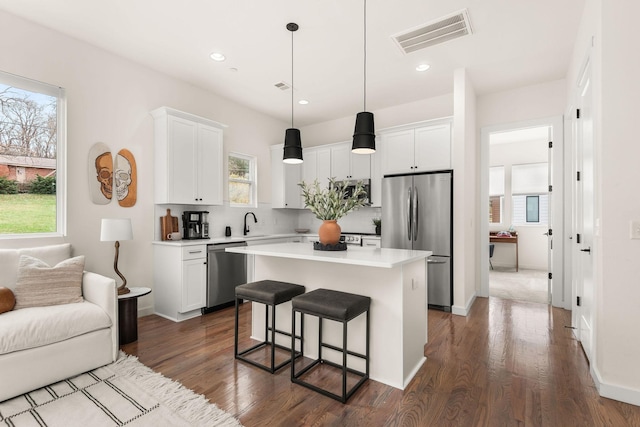 kitchen with white cabinets, a center island, a healthy amount of sunlight, and stainless steel appliances