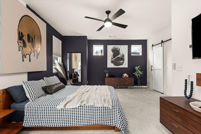 bedroom with light carpet, a barn door, and ceiling fan