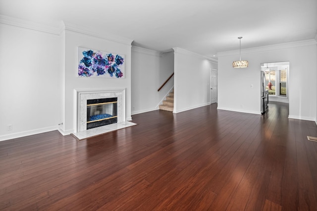 unfurnished living room with a notable chandelier, dark hardwood / wood-style flooring, ornamental molding, and a fireplace