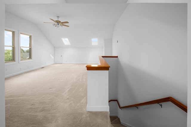 bonus room featuring vaulted ceiling with skylight, ceiling fan, and light colored carpet