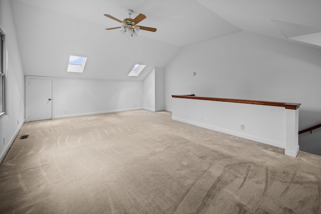 bonus room featuring vaulted ceiling with skylight, ceiling fan, and light carpet