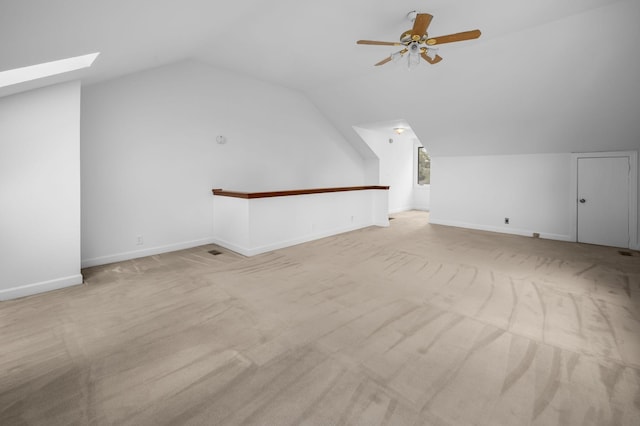 bonus room featuring light carpet, ceiling fan, and vaulted ceiling with skylight