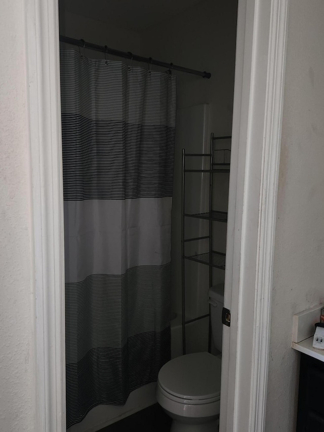 bathroom featuring toilet and curtained shower