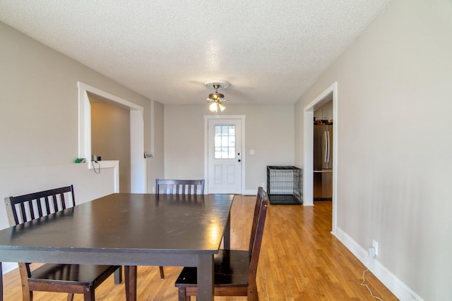 dining room with ceiling fan, light hardwood / wood-style floors, and a textured ceiling