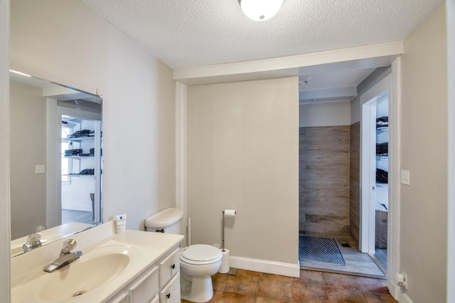 bathroom featuring a shower, a textured ceiling, vanity, and toilet