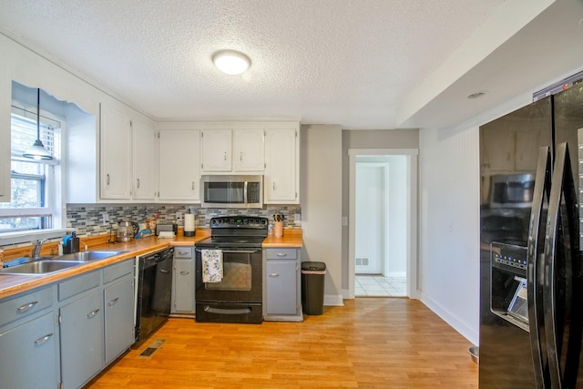 kitchen featuring black appliances, wood counters, white cabinets, and sink