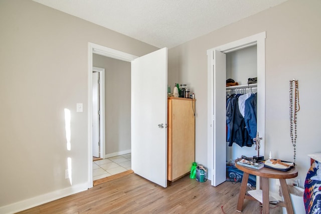 bedroom with a textured ceiling, light wood-type flooring, and a closet