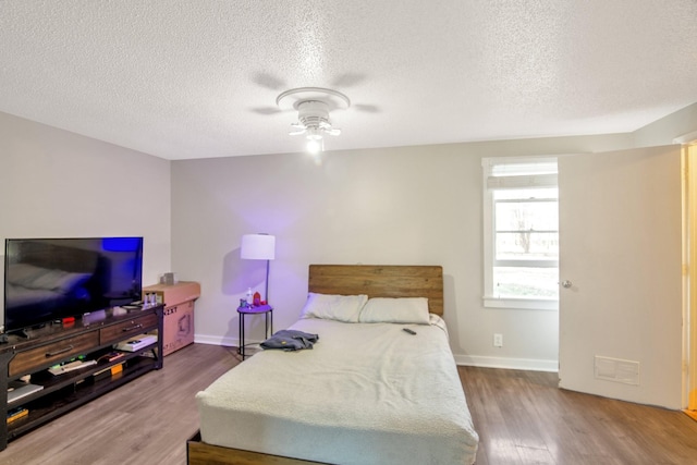 bedroom with a textured ceiling, hardwood / wood-style flooring, and ceiling fan