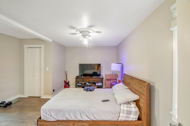 bedroom with a textured ceiling, light hardwood / wood-style floors, and ceiling fan