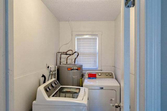 laundry room with washing machine and clothes dryer, a textured ceiling, and water heater