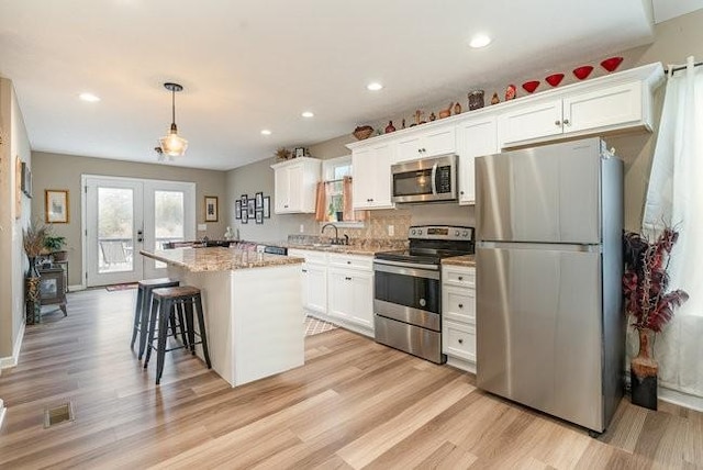 kitchen featuring stainless steel appliances, a center island, and white cabinets