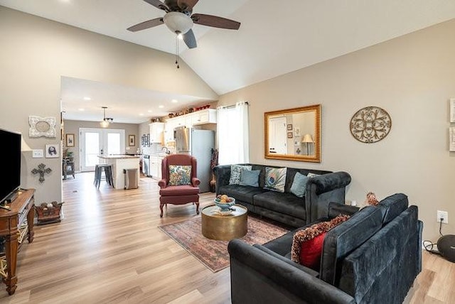 living room with ceiling fan, vaulted ceiling, and light hardwood / wood-style flooring