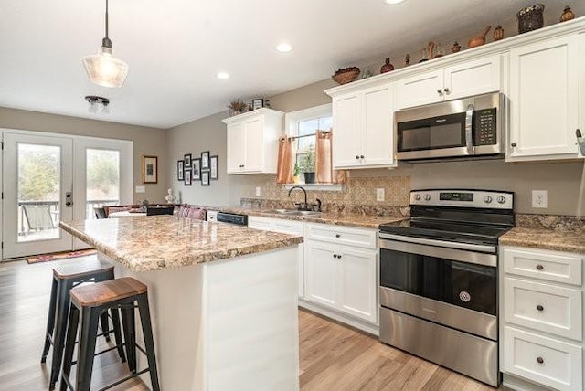 kitchen with stainless steel appliances, hanging light fixtures, sink, and white cabinets