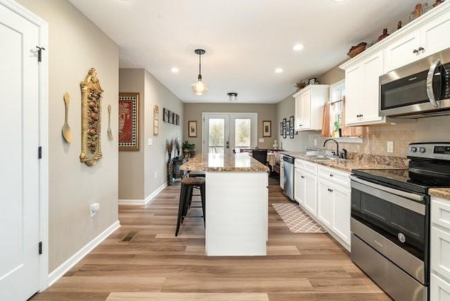 kitchen featuring a kitchen island, appliances with stainless steel finishes, a breakfast bar area, white cabinets, and french doors