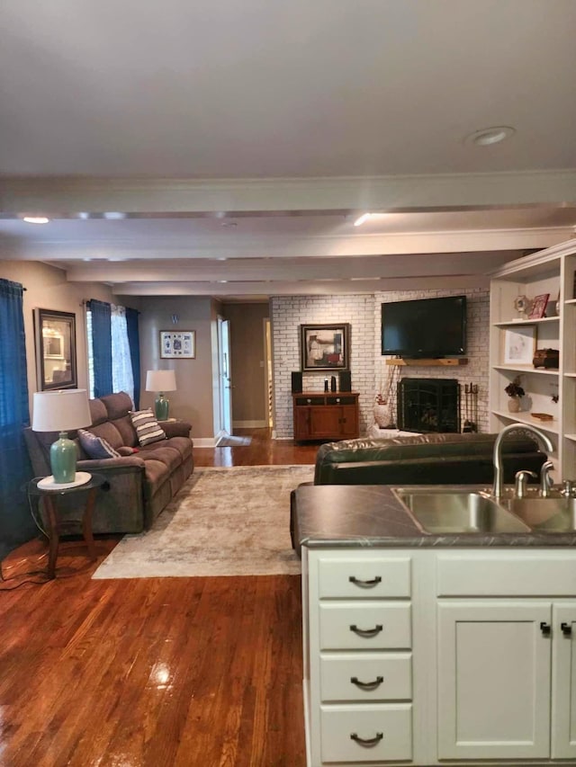 interior space featuring beamed ceiling, dark hardwood / wood-style flooring, sink, and a brick fireplace