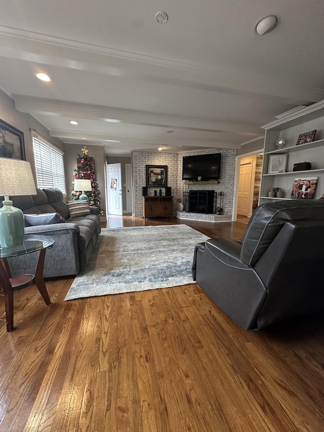 living room featuring beam ceiling, a fireplace, brick wall, and hardwood / wood-style flooring