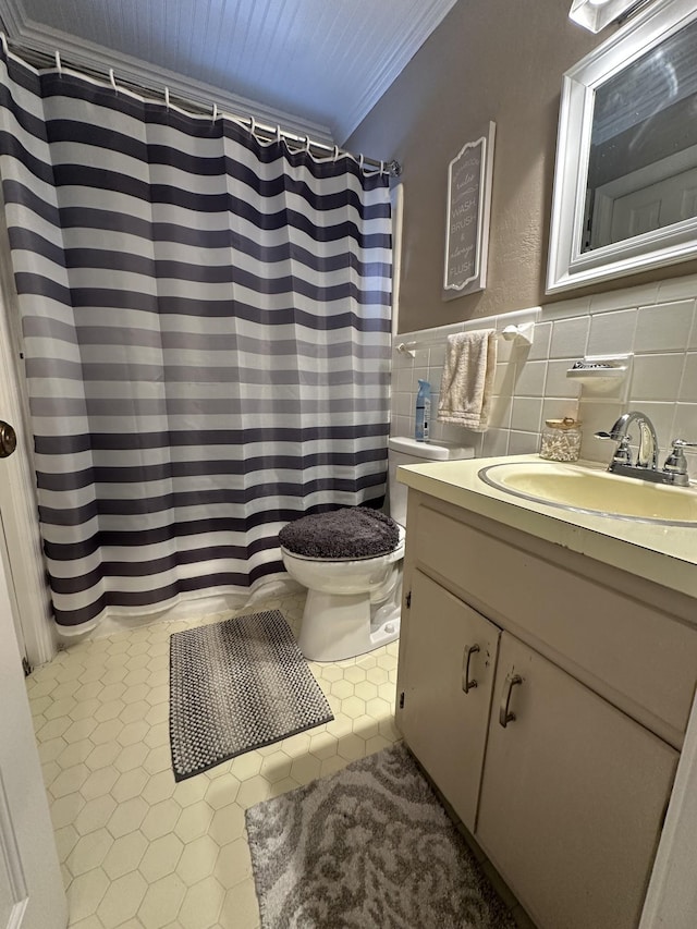 bathroom featuring vanity, toilet, ornamental molding, and tile walls