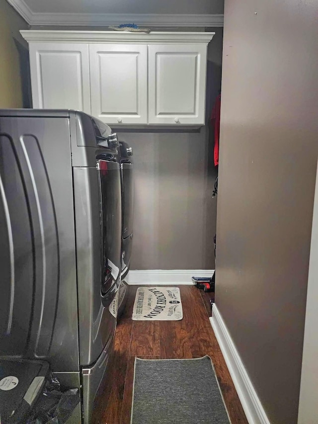 clothes washing area featuring cabinets, dark hardwood / wood-style flooring, washer and dryer, and ornamental molding