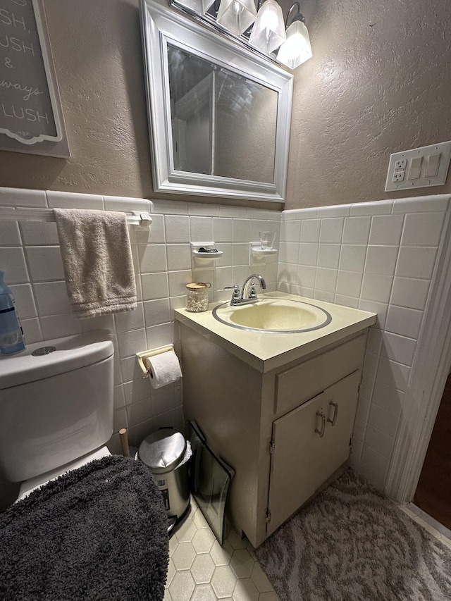 bathroom featuring tile patterned floors, vanity, tile walls, and toilet