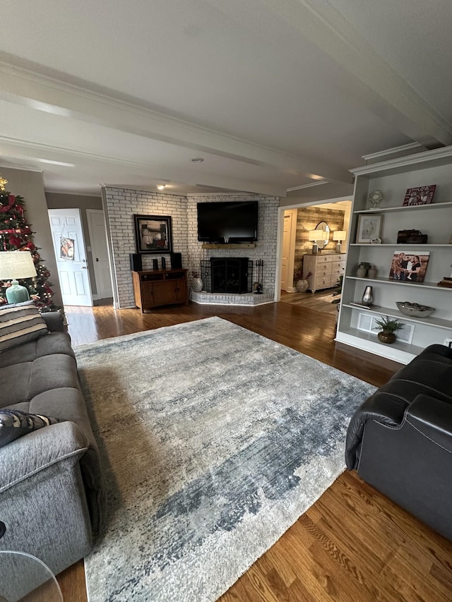 living room featuring beam ceiling, dark hardwood / wood-style floors, a brick fireplace, and brick wall