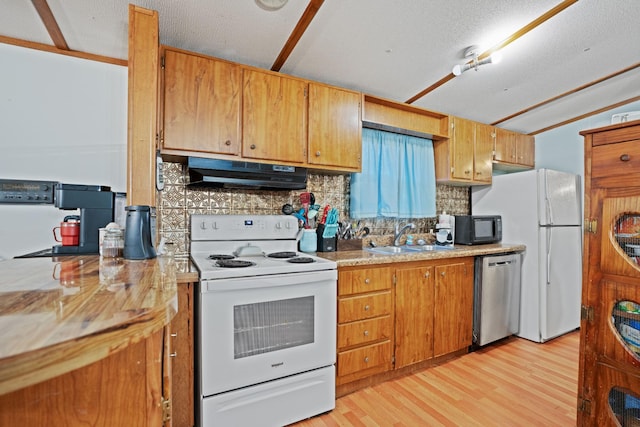 kitchen with sink, tasteful backsplash, light hardwood / wood-style flooring, a textured ceiling, and white appliances