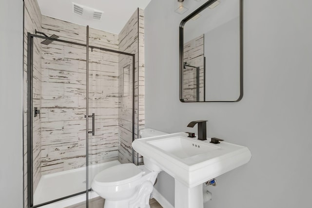 bathroom with toilet, a shower with shower door, and sink