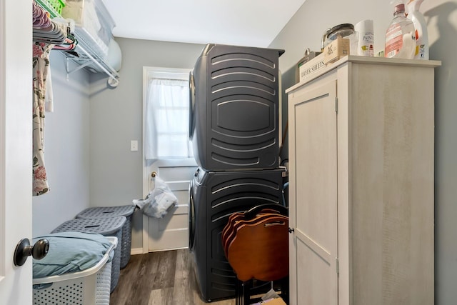 laundry room featuring laundry area, stacked washing maching and dryer, and dark wood-type flooring