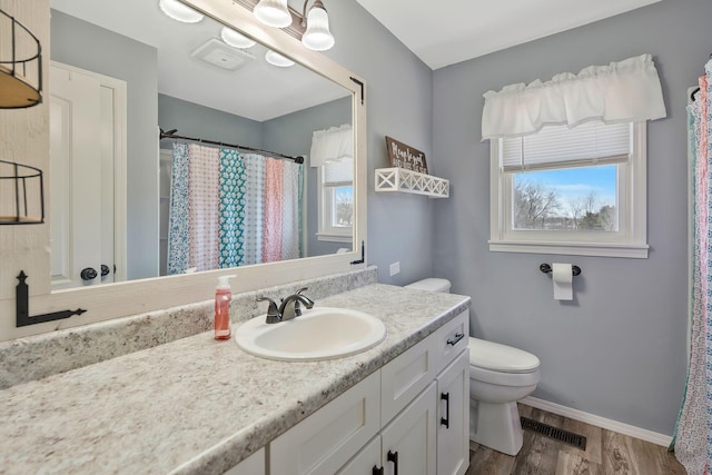 bathroom with visible vents, toilet, vanity, wood finished floors, and baseboards